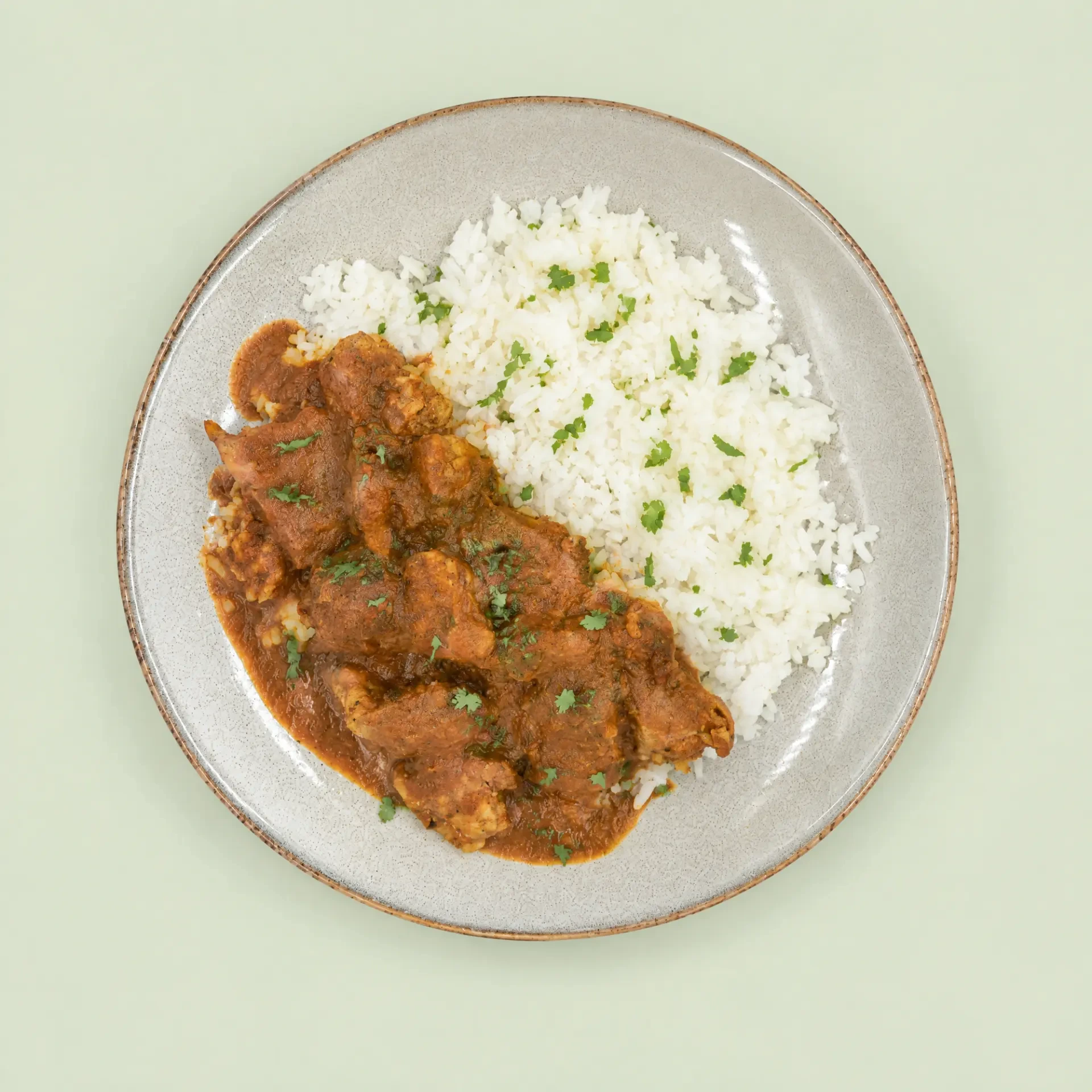 Butter Chicken & Rice served on a ceramic plate with herb garnish