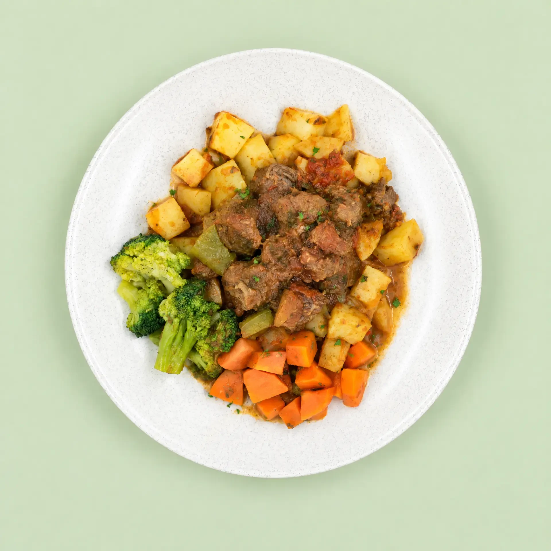 Beef Goulash & Potato served on a plate with broccoli and carrots